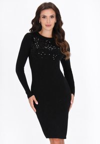 Abito lungo a maniche lunghe nero con effetto a coste, caratterizzato da un upper decorato con paillettes, una silhouette aderente e un orlo che arriva al ginocchio. Morbido al tatto.