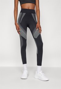 Leggings negre cu talie înaltă, modele gri contrastante și accente cu puncte. Fabricate din material elastic pentru confort și potrivire.