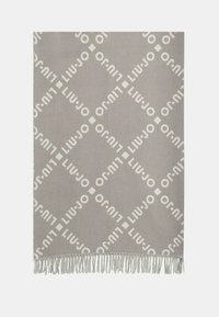 Couverture gris clair avec un motif en diamant et du texte de marque répété en blanc. Bords terminés par des franges décoratives.