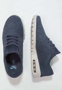 Marina mockasiner i mocka med låg topp, utrustade med en beige gummisula och luftdämpning, snörstängning och diskret loggdetalj.