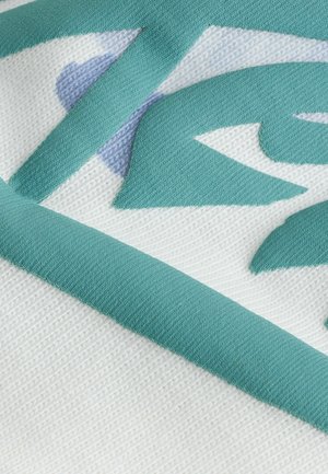 Gestructureerde stof in het wit met teal en lichtblauwe abstracte patronen, met een effen teal rand. Close-up detail van het ontwerp.