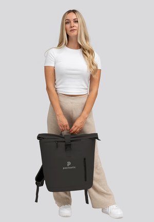 Sac à dos gris à rabat avec fermeture à boucle, poche zippée à l'avant et logo. Texture lisse, bretelles ajustables et design minimaliste.
