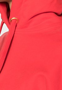 Rode hoodie gemaakt van zacht materiaal, met een trekkoord en gouden hardware, een gladde textuur en een ontspannen pasvorm.