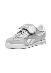 Sneaker Reebok argento e bianco con lacci, una fascia in Velcro e loghi brandizzati sulla linguetta e sul lato, mostrato su uno sfondo bianco.