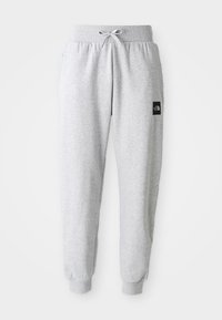 Lys grå sweatpants med elastisk talje, snorelukning, manchetter ved anklerne og et lille sort rektangulært logo på højre lår.