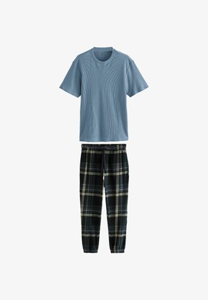 Sinine ribadega lühikeste varrukatega T-särk mustade ruuduliste pükste peal, millel on elastne vöökoht. Pükstel on halli, kreemi ja sinise värvi jooned mustris.