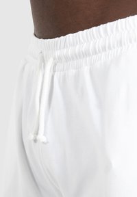 Weiße Shorts mit einem elastischen Bund und Kordelzug, aus weichem Stoff gefertigt und mit einer strukturierten Oberfläche.