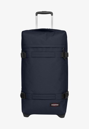 Navy fabric roller suitcase with black hardware, adjustable straps, and a retractable handle. Features a logo patch on the front.