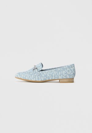Light blue loafers made of textured fabric, featuring a decorative ring accent and a flat wooden heel. Simple, elongated shape.