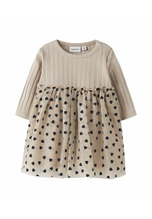 Abito a maniche lunghe con parte superiore a coste beige e gonna beige decorata con motivi a cuori neri, rifinito con una cucitura arricciata in vita.