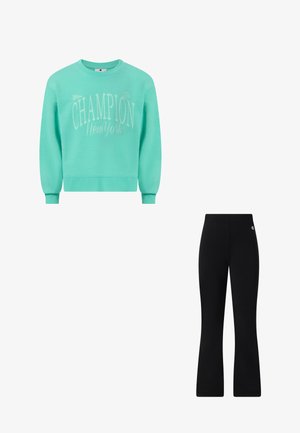 Aqua Champion New York-trui gecombineerd met zwarte uitlopende Champion-logo broek.