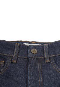 Tummansinisiä farkkuhousuja, joissa on keltainen ommel, etumainen nappisulku ja pyöreä metallinen logo-nappi.