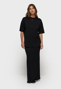 Set di maglietta nera oversize e gonna maxi, realizzato in tessuto morbido. La maglietta presenta maniche corte e scollatura a girocollo; la gonna è aderente.