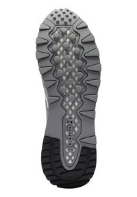 Semelle de chaussure en caoutchouc gris et noir, avec des crampons circulaires en relief, un motif en losange au centre, et le logo "Reebok" le long du milieu.