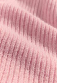 Svetloružová rebrovaná látka s jemnou, chlpatou textúrou. Povrch má vertikálne, rovnomerne rozložené ryhy.