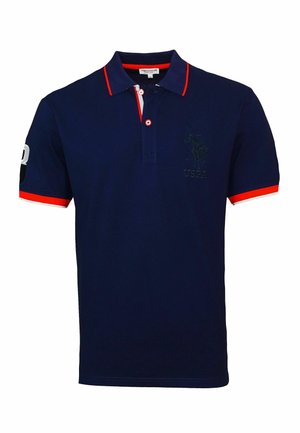 Polo shirt bleu marine en coton doux. Présente des accents rouges sur le col et les manches, avec un logo brodé sur la poitrine.