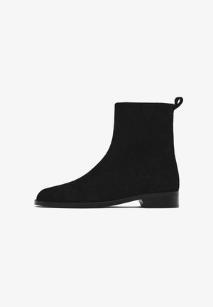 Bottines en daim noir avec une texture lisse, un bout arrondi et un petit talon empilé. Une languette à l'arrière facilite l'enfilage.