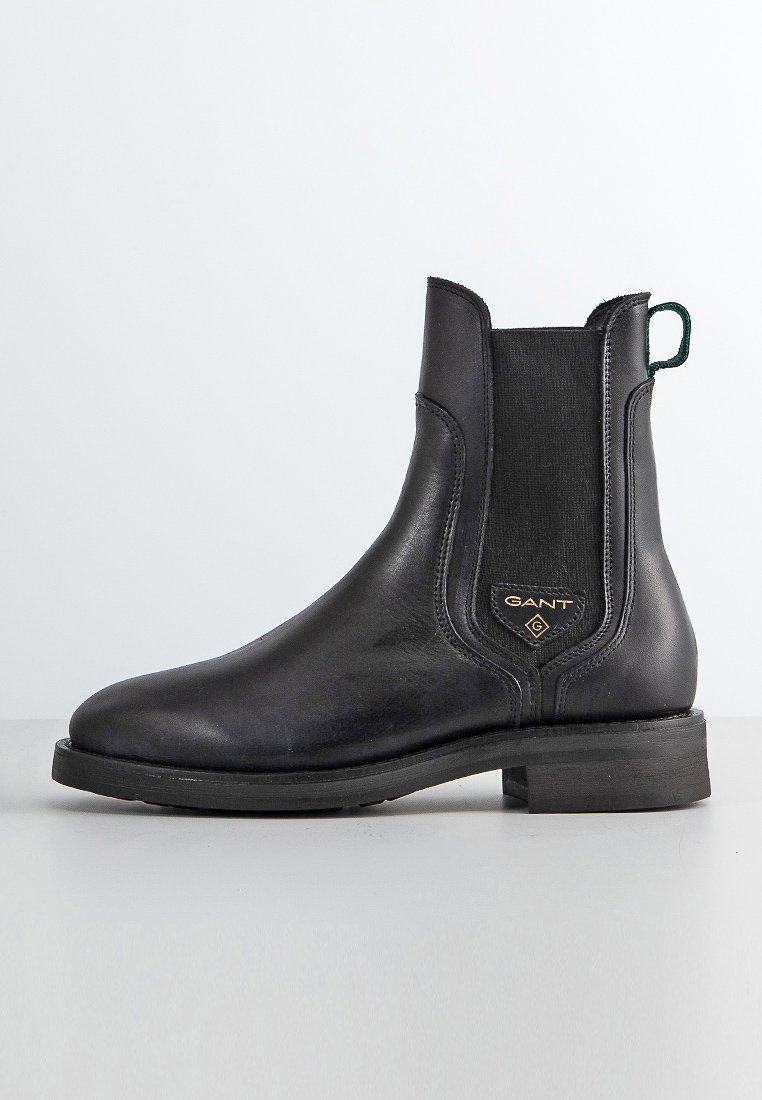 Schwarze Leder Chelsea-Stiefel mit elastischen Seitenpaneelen, runder Zehenform, niedrigem Blockabsatz, grünem Schlaufenanhänger und goldfarbenem Logo-Detail an der Seite.