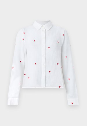Άσπρο πουκάμισο με μακριά μανίκια και κουμπιά, με κόκκινα κεντημένα σχέδια καρδιών και μυτερό γιακά, εμφανισμένο σε ουδέτερο φόντο.