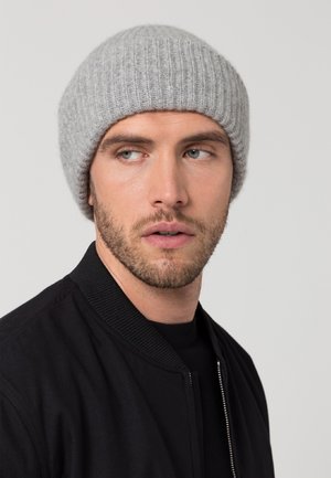 Berretto a coste grigio realizzato in materiale morbido, indossato con una giacca bomber nera. Il berretto ha una parte superiore arrotondata e una vestibilità aderente attorno alla testa.