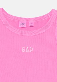 Ροζ ριμπ μπλούζα με στρογγυλή λαιμόκοψη, που διαθέτει ένα μικρό, κεντημένο λογότυπο "GAP" σε λευκό στο στήθος. Η ετικέτα μεγέθους υποδεικνύει L (10).