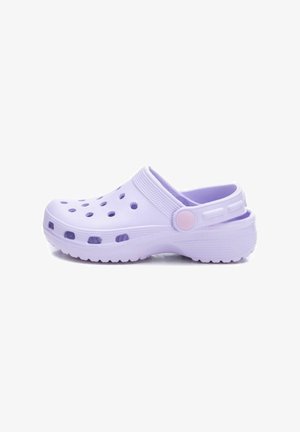 Zueco de plástico de color púrpura claro con un diseño de slip-on, punta redondeada, orificios de ventilación y una correa trasera con un botón rosa. Suela texturizada.