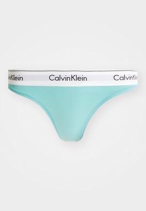 Light teal thong with a white band featuring "Calvin Klein" in black lettering. Smooth texture, minimalist design, and ergonomic shape.