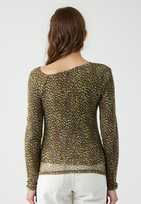 Haut transparent à manches longues avec un décolleté asymétrique, arborant un motif multicolore dans des teintes de marron, vert et blanc.