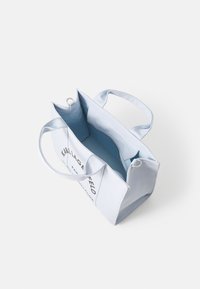 Borsa a tracolla di tela blu chiaro con due manici, zip sulla parte superiore e interno blu a contrasto. Presenta un testo stampato sulla parte anteriore.