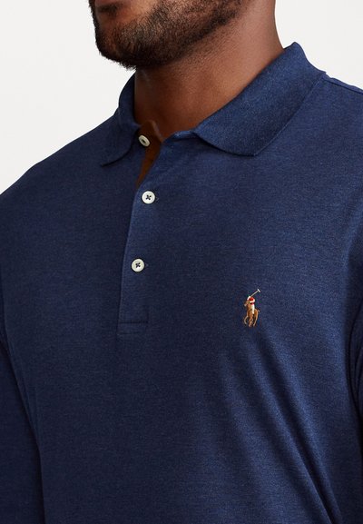 Marineblauwe polo shirt gemaakt van een katoenmix beschikt over een klassieke kraag, vier knopen en een geborduurd logo. Glad oppervlak met een subtiele glans.