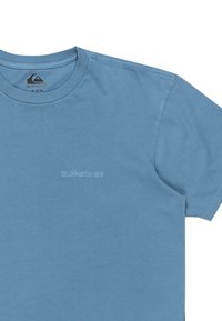 Blå t-shirt med kort ärm i bomull. Har en rund halsringning och en broderad "Quiksilver"-logotyp i en ljusare blå nyans.