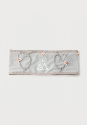 Light grey fabric belt with ACG logo, featuring two loops each holding an orange and white cord with toggle closures.