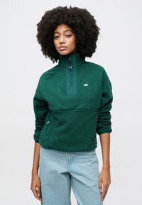 Grønn fleecegenser med halvlang glidelåskrage. Har et brystpanel og to sidelommer; myk tekstur med en logo-detalj.