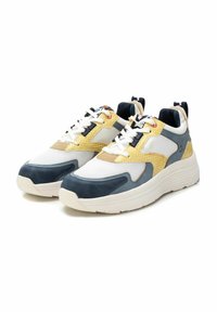 Sneakers bianchi testurizzati con accenti blu navy e gialli, dotati di una tomaia in rete e suola in gomma, progettati con una forma sportiva e moderna.