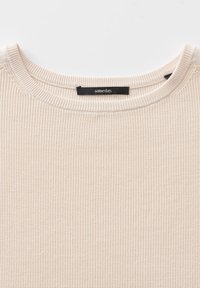 Maglione a coste color beige chiaro con scollatura rotonda e un'etichetta nera con la scritta "un giorno." Texture liscia con sottili linee verticali.