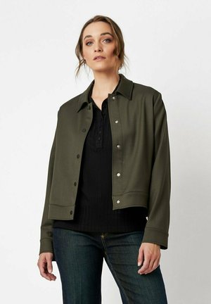 Grüne, leichte Jacke mit Kragen und Druckknöpfen, kombiniert mit einem schwarzen Rippoberteil. Glatte Textur, lässige Passform.