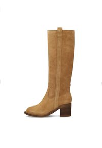 Botte en suède beige montante avec un bout arrondi, des détails de couture verticale et un talon empilé. Texture lisse avec un design minimaliste.