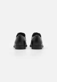 Scarpe in pelle nera con una finitura liscia, punta arrotondata, tacco basso e design minimalista. Nessun hardware visibile o accentuazioni decorative.
