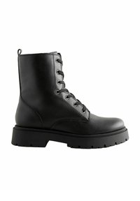 Botas de tobillo negras hechas de cuero sintético texturizado, con un cierre de cordones en la parte delantera, ojales metálicos circulares y una suela de goma gruesa.