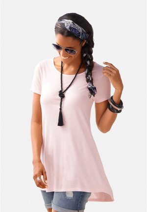 Light pink t-shirt with a round neck, short sleeves, and a high-low hemline, paired with denim shorts and layered necklaces.