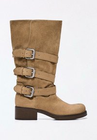 Botte en daim camel mi-mollet avec trois brides à boucles réglables et un talon bas empilé.