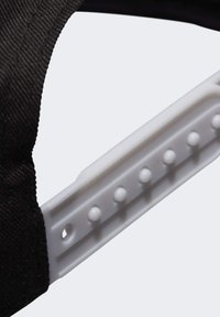 Cappello nero con cinturino e regolatore in plastica bianca, caratterizzato da molteplici tacche rotonde per la regolazione della taglia. Tessuto resistente con finitura texture.