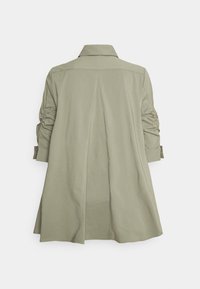 Cappotto verde oliva con colletto, maniche arricciate e design con spacco sul retro. Realizzato in tessuto morbido con una vestibilità rilassata e fluida.