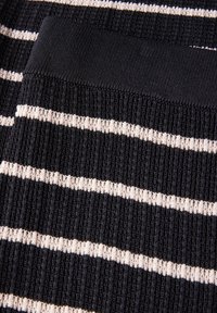 Top in tessuto a maglia con strisce orizzontali nere e crema, coste testurizzate e un collo a coste nere e solide.