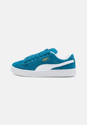 Niebieskie zamszowe niskie tenisówki z białą podeszwą, białym paskiem Puma formstrip oraz złotym logo Puma Suede XL z boku.