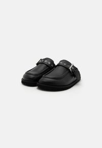 Chaussures noires en cuir à enfiler avec un bout arrondi, dotées d'une sangle et d'un matériel décoratif en argent avec des œillets le long de la sangle.