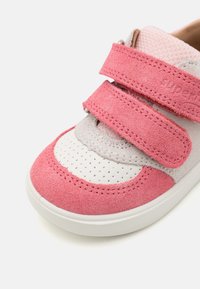 Růžová nubuková a šedá textilní bota se dvěma suchými zipy, perforovanou bílou špičkou a bílou gumovou podrážkou. Zaoblená špička s detailem šití.