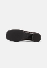 Pantof brown din piele cu un model texturat de crocodil. Dispune de o talpă din cauciuc netedă, cu nervuri pentru aderență și un toc mic, rotund.