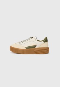 Lave sneakers med beige, olivengrønn og hvit overdel, brun gummisåle, grå snører og gull "SOREL" logo på siden.