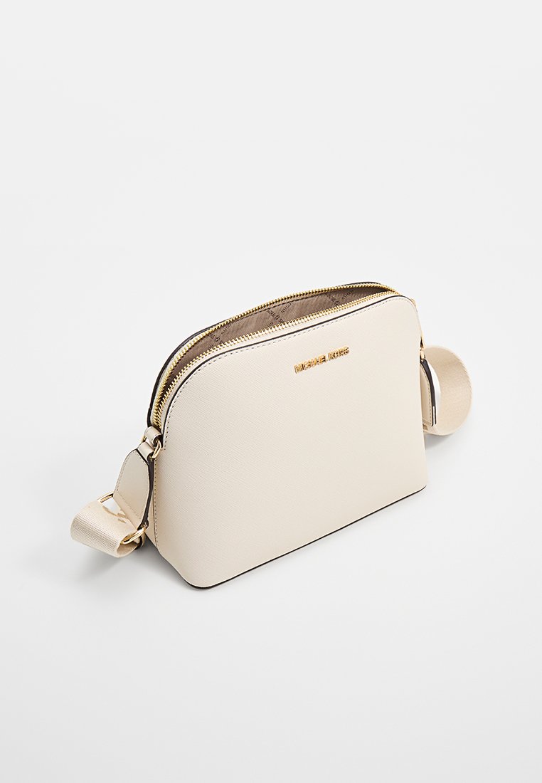 Pequeño bolso cruzado de color beige hecho de material sintético texturizado. Presenta herrajes en tono dorado, un doble cierre de cremallera y una correa desmontable.